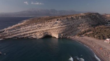 Akdeniz arazisi, Yunan sahil taşlı insansız hava aracı hala tanımlanamayan banyolarla çekiliyor. Girit adasındaki Matala kireçtaşı mağaralarının hava günü manzarası. Şemsiyeli sakin deniz yatakları..