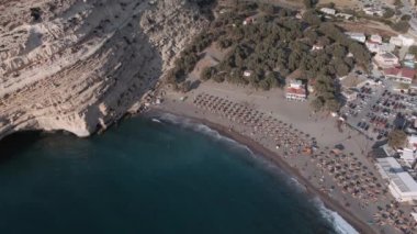 Akdeniz arazisi, Yunan sahil taşlı insansız hava aracı hala tanımlanamayan banyolarla çekiliyor. Girit adasındaki Matala kireçtaşı mağaralarının hava günü manzarası. Şemsiyeli sakin deniz yatakları..