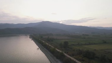 Terk edilmiş bir evle birlikte göl kenarındaki toprak yolun yanındaki yeşil ağaçlı arazi antenleri. Kuzey Yunanistan 'daki Kerkini su alanının İHA görüntüsü. 
