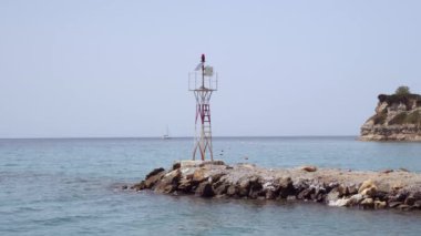 Demir inşaat güneş enerjisiyle çalışan fener taştan bir deniz bariyerinin sonunda. Yunanistan 'ın Chalkidiki kentindeki Kassandra yarımadasında kıyı kenarında seyrüsefer yardımı yapılan dalgakıran yapısının gündüz görünümü.