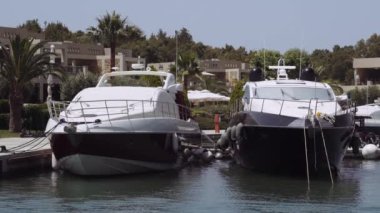 Yunanistan 'ın Sani kentindeki modern bir marinadaki villaların önünde demirlemiş lüks gemiler. Kassandra Chalkidiki yarımadasındaki bir limandaki yatların gündüz görüntüsü her türlü kapıcı hizmeti sunuyor..