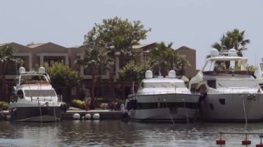 Yunanistan 'ın Sani kentindeki modern bir marinadaki villaların önünde demirlemiş lüks gemiler. Kassandra Chalkidiki yarımadasındaki bir limandaki yatların gündüz görüntüsü her türlü kapıcı hizmeti sunuyor..