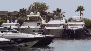 Yunanistan 'ın Sani kentindeki modern bir marinadaki villaların önünde demirlemiş lüks gemiler. Kassandra Chalkidiki yarımadasındaki bir limandaki yatların gündüz görüntüsü her türlü kapıcı hizmeti sunuyor..