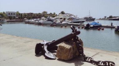 Yunanistan 'ın Sani kentindeki modern bir marinadaki villaların önünde demirlemiş lüks gemiler. Kassandra Chalkidiki yarımadasındaki limandaki yatların gündüz görüntüsü. Zincirli güverte dekorlu büyük bir çapa..