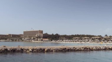 Otel villaları deniz manzarası, deniz tabanında şemsiyeli plaj banyoları. Yunanistan 'ın Kassandra Chalkidiki yarımadasındaki Sani lüks tatil beldesinin yeşil bitki örtüsüyle çevrili gündüz manzarası.