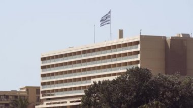 Otel kompleksinin tepesinde Yunan bayrağı sallanıyor. Kassandra Chalkidiki yarımadasında balkonlu Sani lüks kompleksinin gündüz manzarası.
