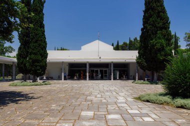 Olympia, Yunanistan Arkeoloji Müzesi 'nin ziyaretçilerle dolu avlu girişi. Klasik zamanlarda antik spor oyunlarına ev sahipliği yapan alandan gelen sergilerle dış yapı inşa etmek.