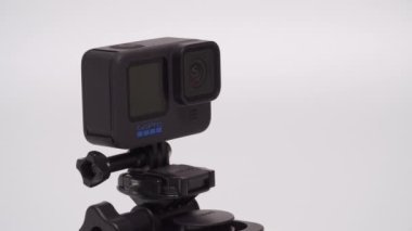 GoPro Kahraman 10 siyah, mavi logosu dönüyor. Ekrandaki eylem kamerası beyaz arkaplana karşı bir emme kabına monte edildi. 