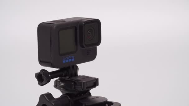 青いロゴが回転するGopro Hero 10黒 白い背景に吸引カップに取り付けられたディスプレイ上のアクションカメラ — ストック動画