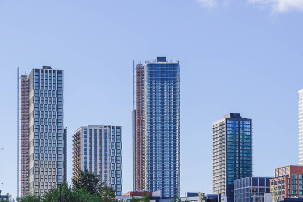 London, UK - September 28, 2024: Tall, modern buildings stand in Canary Wharf, East London, showcasing the city's vibrant architecture against a clear blue sky.