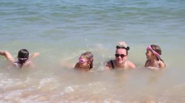 Genç kızları olan genç bir anne sahilde dalgalarda yüzüyor. Yüksek kalite 4k görüntü