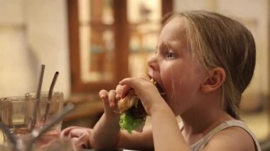 Küçük bir kız restoranda taze sıkılmış meyve suyu içiyor. Yüksek kaliteli FullHD görüntüler