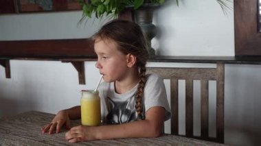 Küçük bir kız restoranda taze sıkılmış meyve suyu içiyor. Yüksek kaliteli FullHD görüntüler