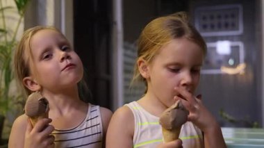 Karanlık bir sokakta dondurma yiyen küçük ikiz kardeşler. Yüksek kaliteli FullHD görüntüler