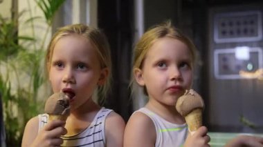 Karanlık bir sokakta dondurma yiyen küçük ikiz kardeşler. Yüksek kaliteli FullHD görüntüler