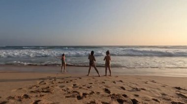 Okyanus sahilindeki dalgalardan kaçan üç küçük kız kardeş. Yüksek kalite 4k görüntü