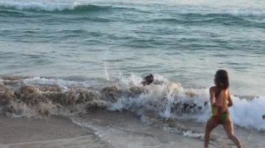 Küçük üçüz kız kardeşler dalgalarda yüzer. Yüksek kalite 4k görüntü
