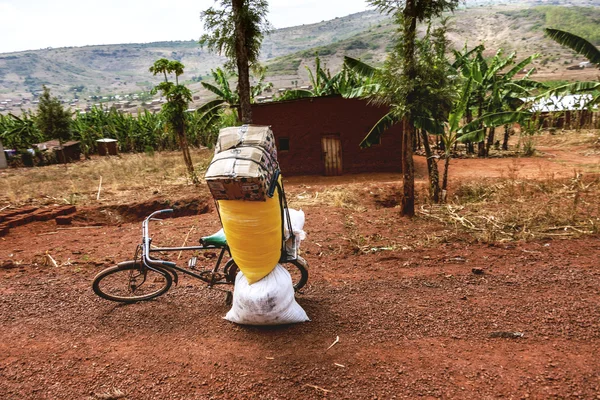 A bicicleta na estrada vermelha da terra está esperando seu proprietário carregar os sacos nele . — Fotografia de Stock