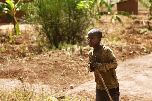 The farmer African child with his stick look across.