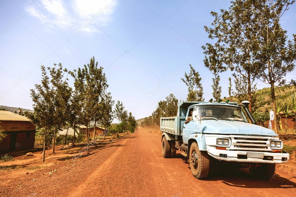 The light blue old truck carrying the workers on the road ...