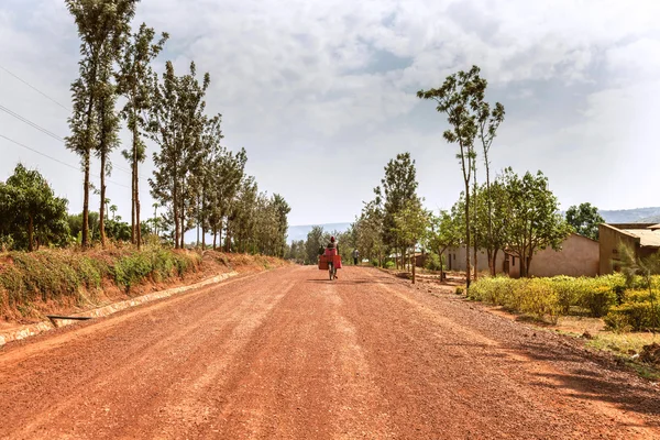 De man die fietsen op rode Afrikaanse aarde. — Stockfoto