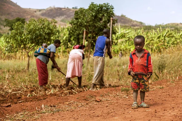 Afrikaanse werknemers nemen hun kinderen langs wanneer ze werken. — Stockfoto