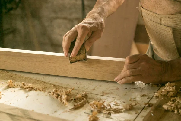 Mans hands working a stick with sandpaper — Stock Photo, Image