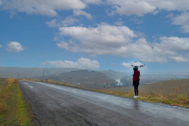 Yolun kenarında şemsiyeli bir kadın.