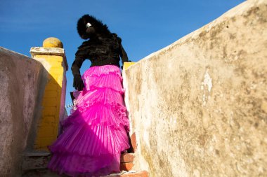 Siyah maskeli, gözlüklü ve kapüşonlu zarif bir kadın.