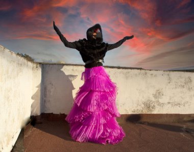 Siyah maskeli, gözlüklü ve kapüşonlu zarif bir kadın.