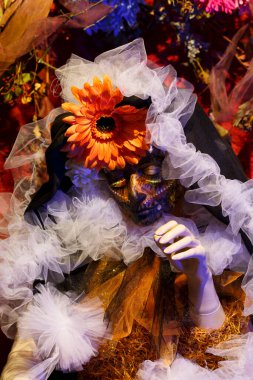 Calavera Catrina karanlık bir arka planda kafatası tutuyor.