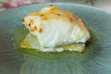 Cam bir tabakta fırınlanmış patatesli morina yemeği.