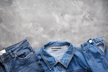 Kadın ceketi ve kot pantolon, gri arka plan, üst manzara. Metin için yer.