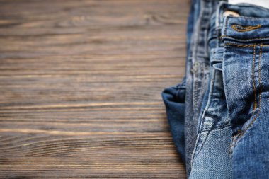 Ahşap arka planda katlanmış kot pantolon, mesaj için yer. Yakın plan..