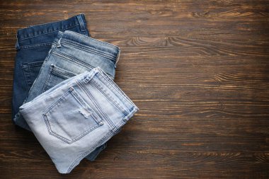 Ahşap arka planda katlanmış mavi kot pantolon, mesaj için yer. Üst görünüm.