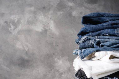 Gri arka planda katlanmış kot pantolon ve metin için yer.