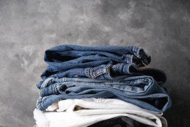 Farklı renklerde kot pantolonlar. Gri arka planda katlanmış kot pantolon, 