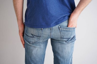 Gri arka planda kot giyen genç bir adamın bacakları..