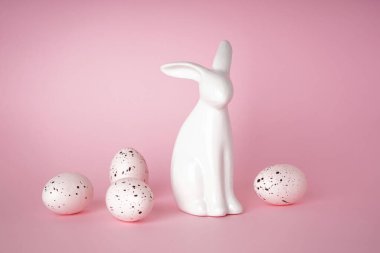 Mutlu Paskalyalar. Paskalya tavşanı ve beyaz paskalya yumurtaları pembe arka planda..