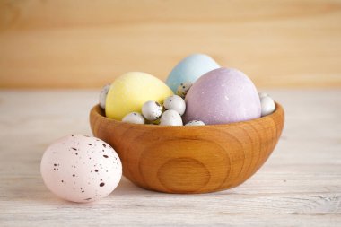 Ahşap arka planda ahşap bir kasede renkli paskalya yumurtaları. Yakın plan.