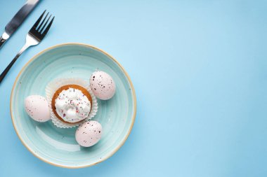 Masa takımı ve mavi arka planda paskalya süslemeleri. Üst görünüm, metin için boşluk.