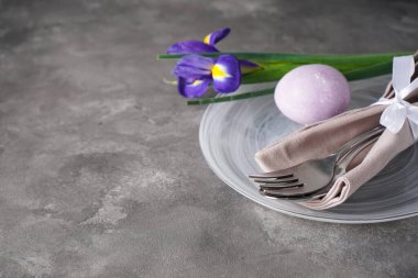 Paskalya bayramı sofrası ve gri arka planda renkli yumurtalarla dolu tabaklar. Paskalya tatili konsepti. Üst görünüm, alanı kopyala.