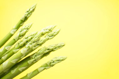 Sarı arka planda yeşil taze kuşkonmaz, mesaj için yer. Yakın plan.