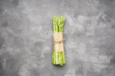 Gri arka planda yeşil taze kuşkonmaz.