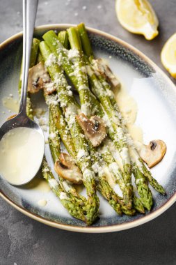 Pişmiş kuşkonmaz ve gri arka planda soslu mantar. Üst görünüm.