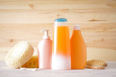 Sabun ve şampuan şişeleri, saç fırçası ve ahşap bir arka planda havlu..