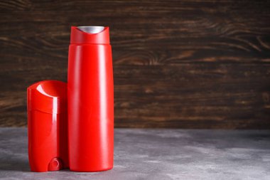 Ahşap arka planda bir şişe şampuan ve deodorant. Metin için boşluk.