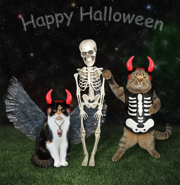 A beige cat in red devil horns holds a trident and hugs a skeleton in the meadow for Halloween.