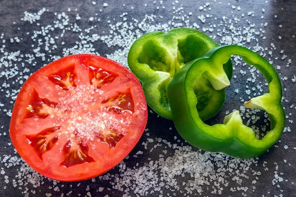 Close-up van verse tomaat op een zwarte achtergrond. Twee stukken van groene peper — Stockfoto