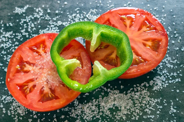 Close-up van verse tomaat op een zwarte achtergrond. Twee stukken van groene peper — Stockfoto